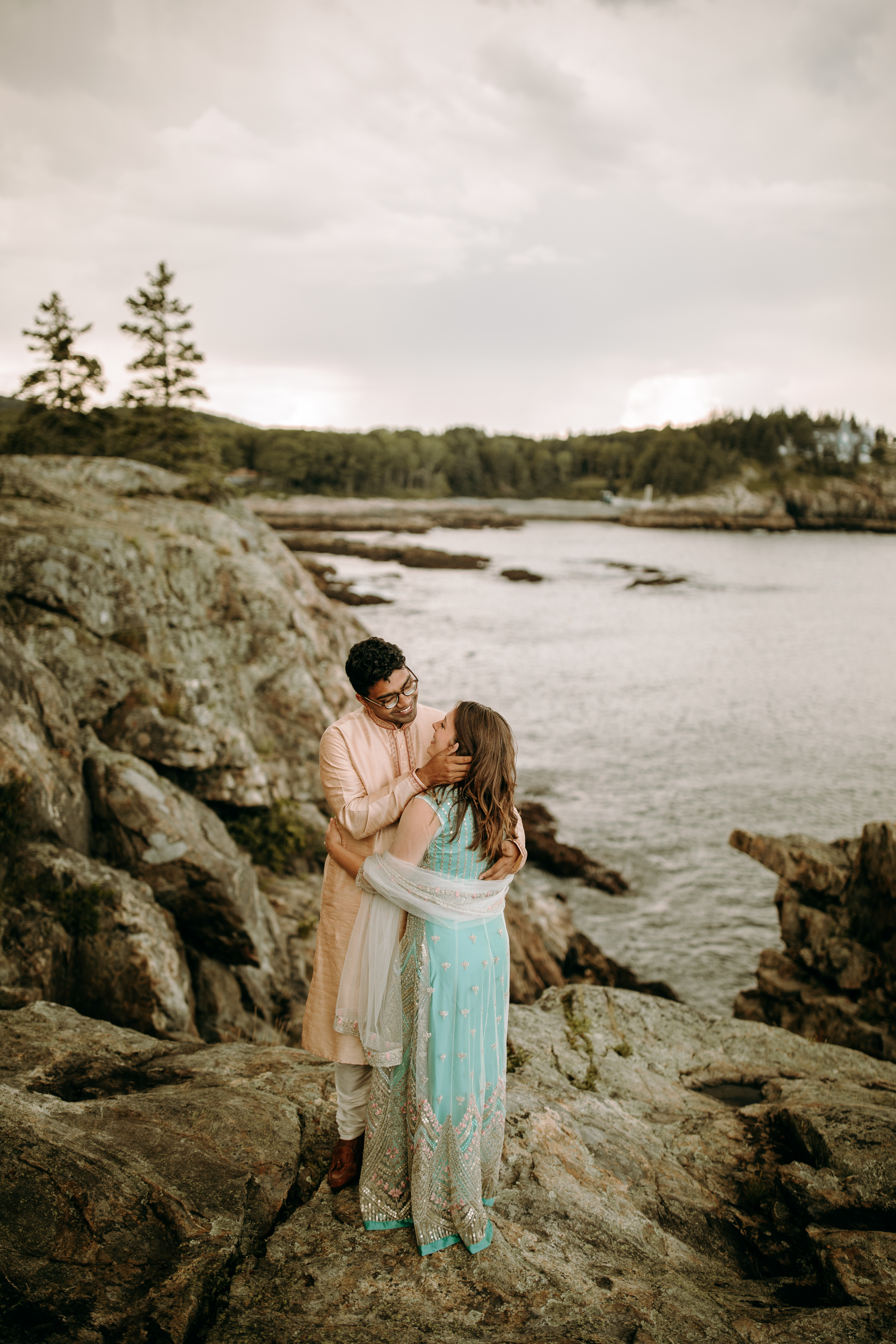Cliff elopement photos on the coast of Maine at Acadia National Park by Schooner Head Point in traditional Indian dress bride and groom standing with ocean in the background in Bar Harbor Maine