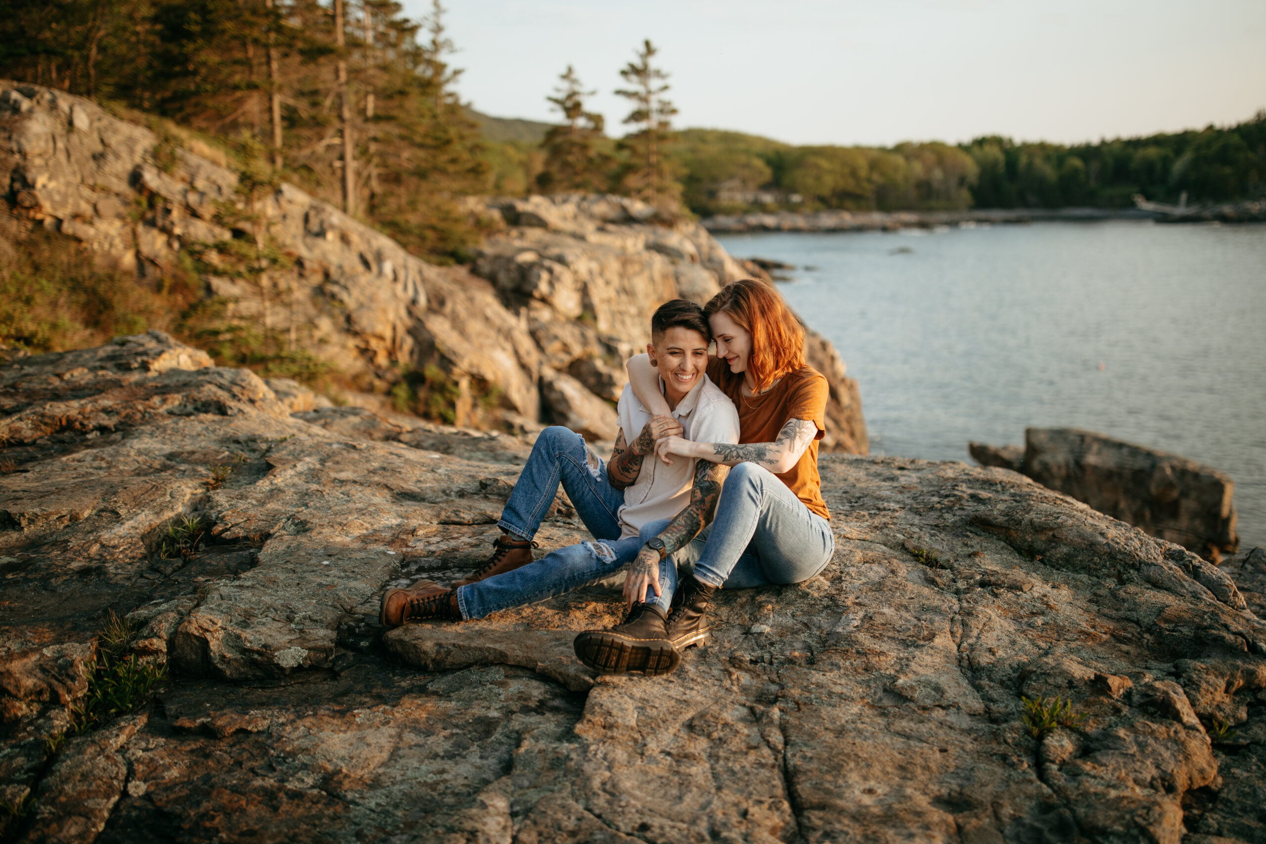 couple sitting on a cliff snuggling for sunrise in Acadia national park during their double proposal