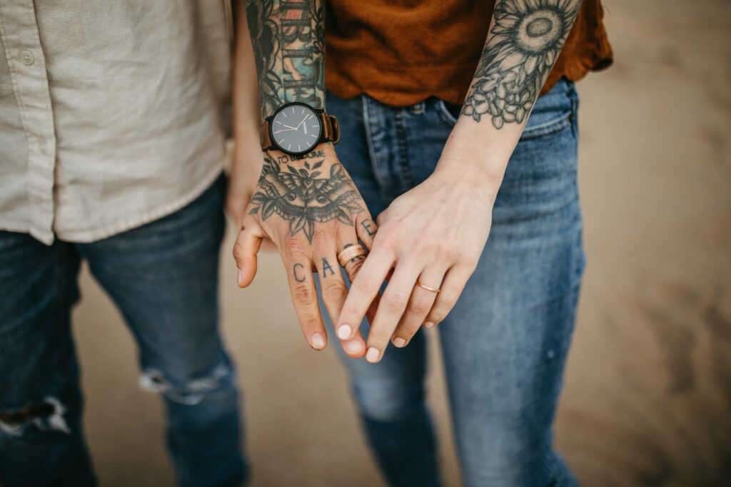 close up photo of rings on both womens hands after proposal tattooed women engagement ring detail photo 