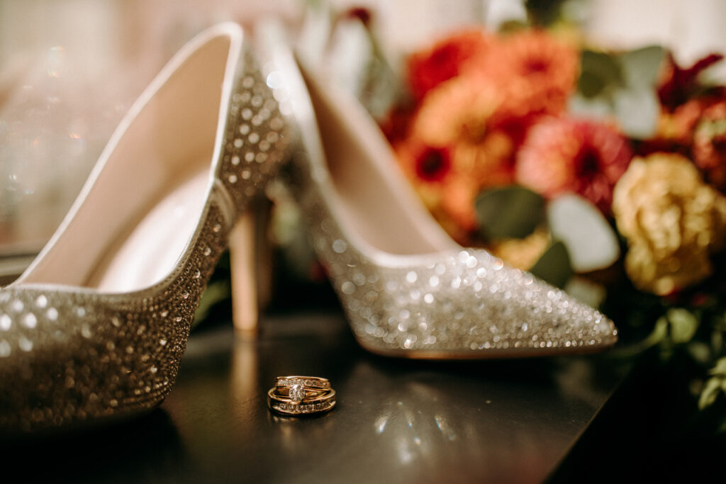 wedding ring detail photo in hotel room with shoes and flowers in the background