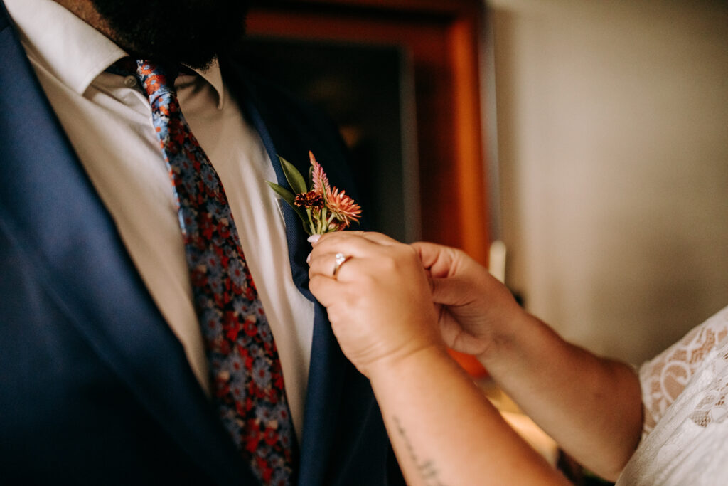Bride helps groom with boutonniere 
