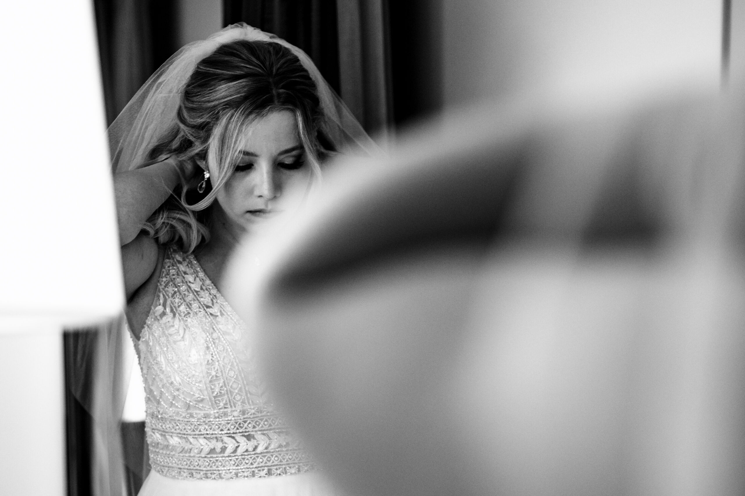 mirror reflection bride in mirror putting on a necklace black and white photo