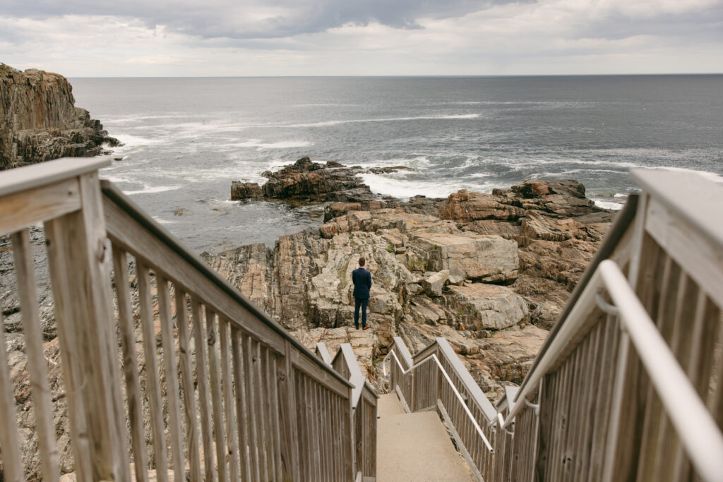 groom waiting for the first look on the cliffs of maine at the cliff house wedding venue in york maine 
