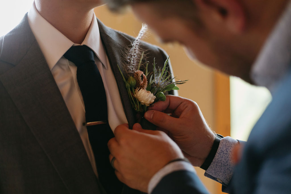 pinning brides boutonniere to her lapel 