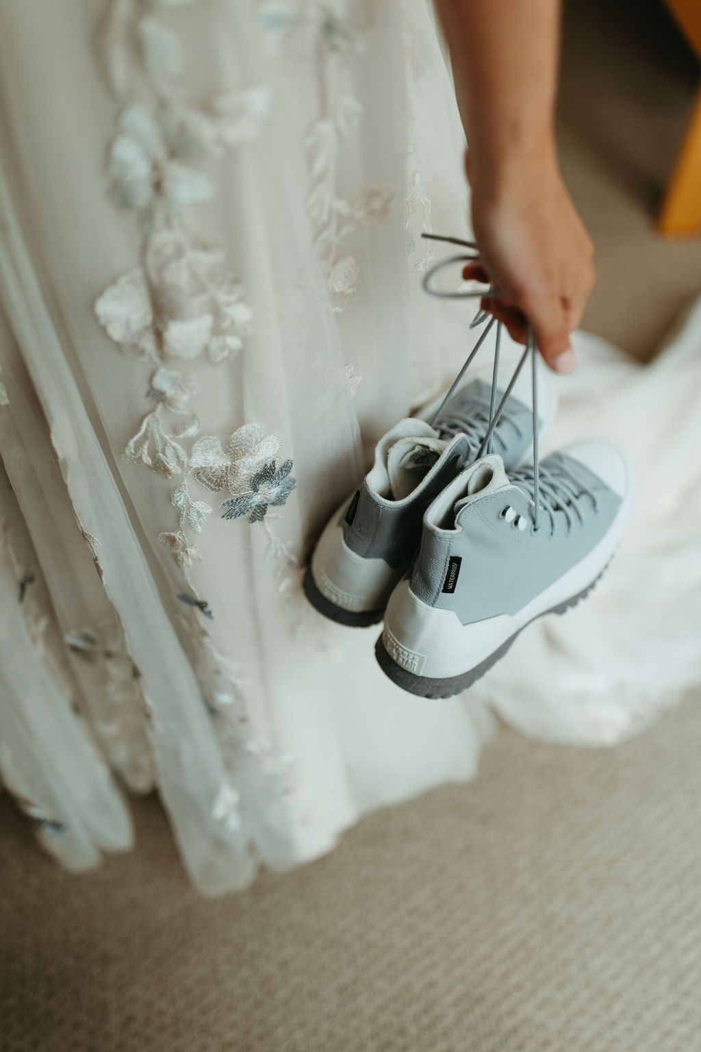bride holding hiking shoes for her outdoor adventurous ceremony at saddleback mountain