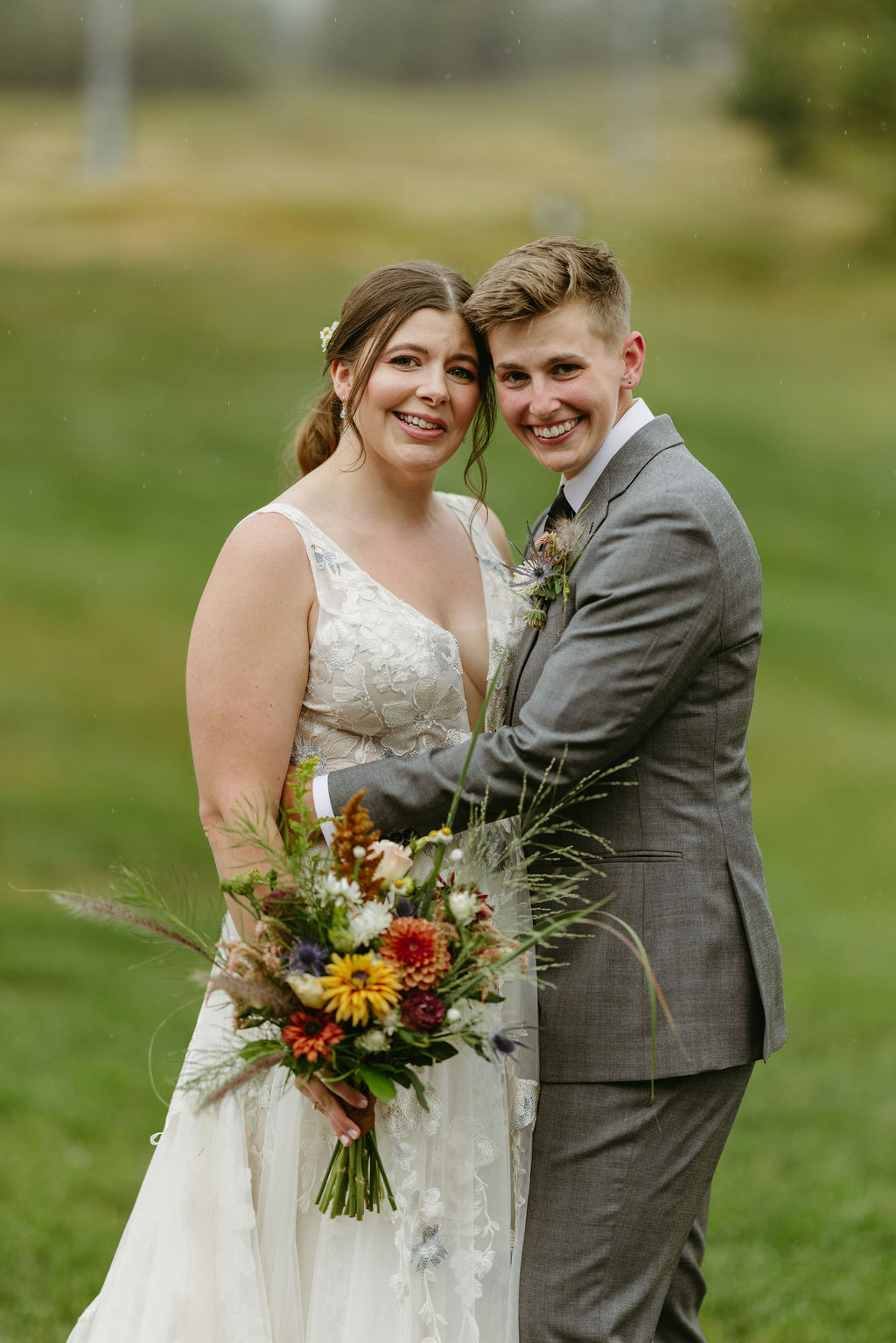 brides smiling at the camera with ski lift mountain behind them at saddleback mountain in rangeley maine 