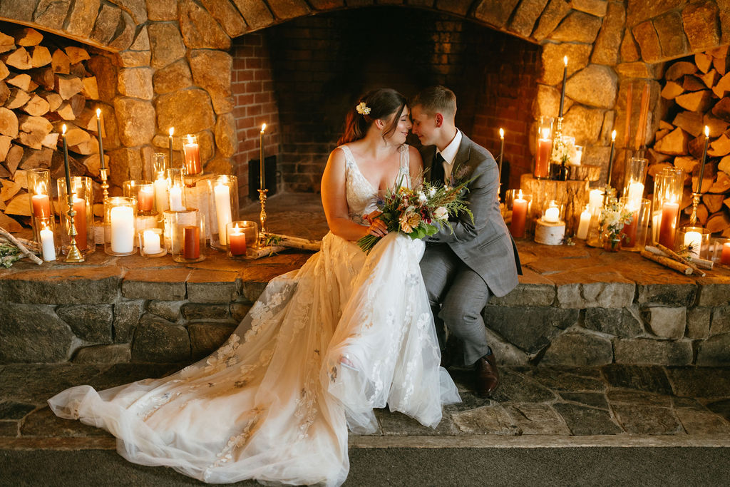 couple sitting in front of candles with fireplace behind them at saddleback mountain wedding venue