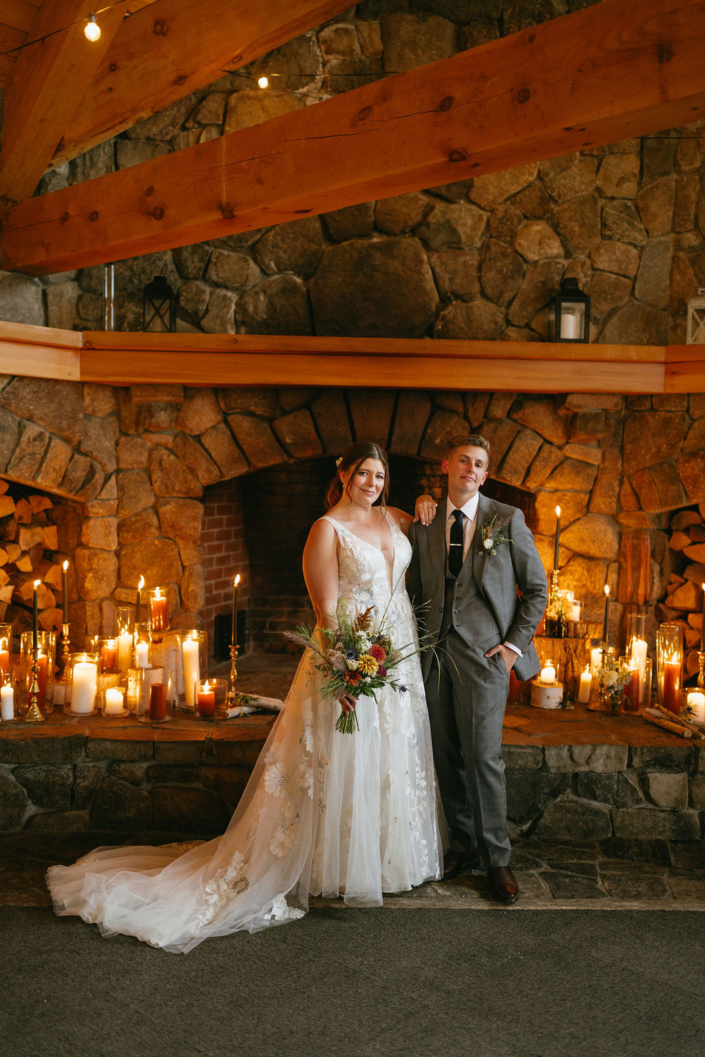couple standing in front of candles with a fireplace behind them at saddleback mountain wedding venue