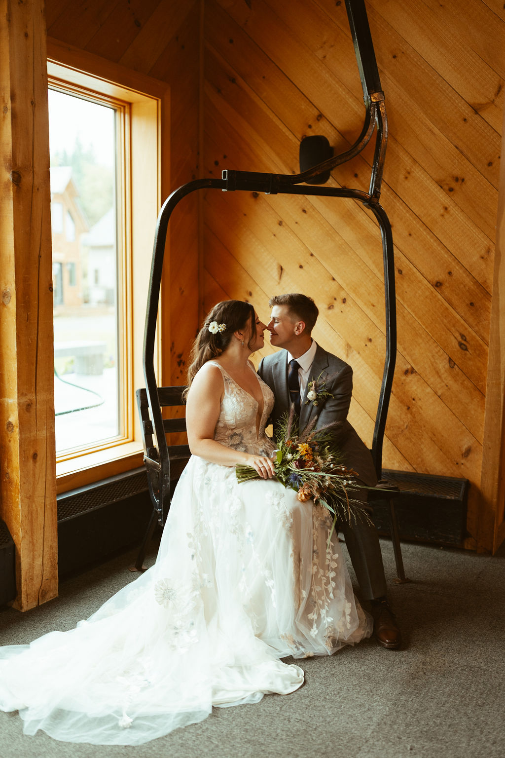 couple snuggled up on ski lift inside at Saddleback Mountain wedding reception venue in Rangeley Maine