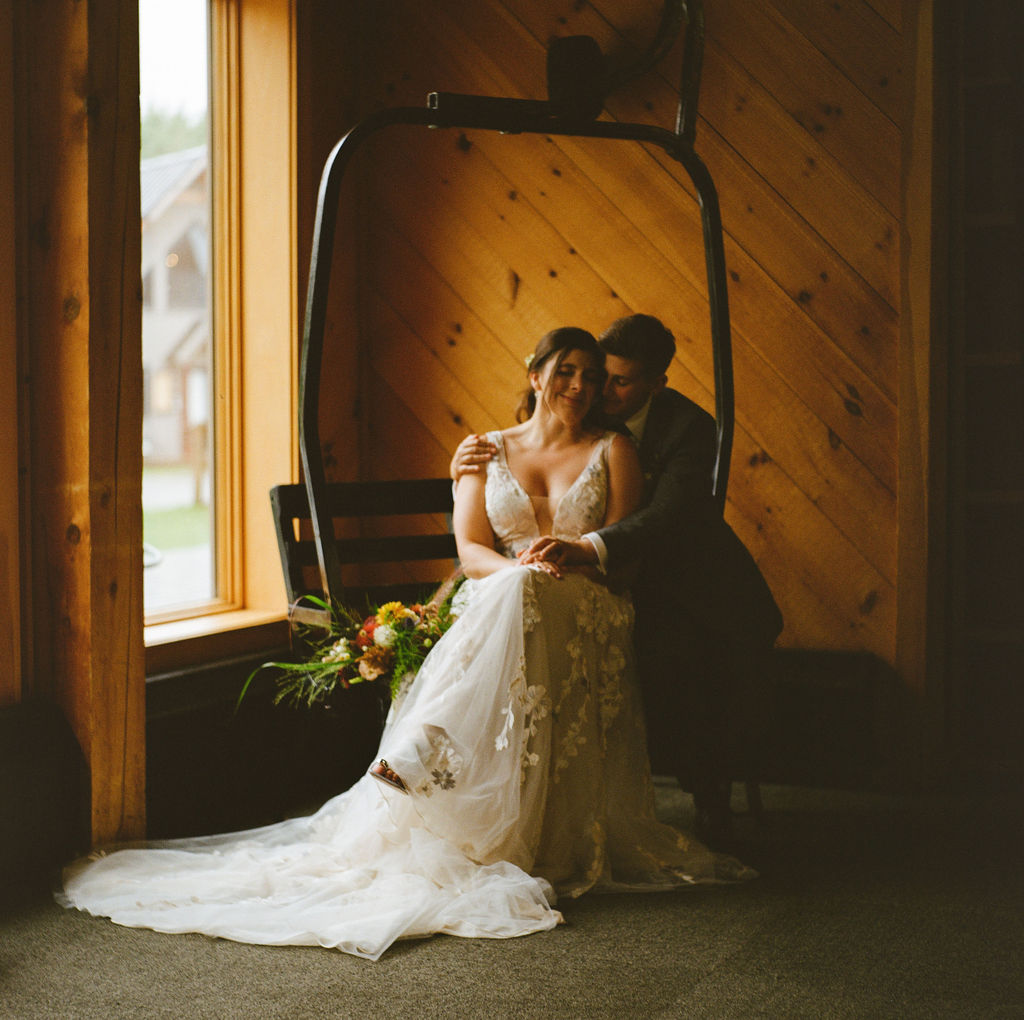 couple snuggled up on ski lift inside at Saddleback Mountain wedding reception venue 